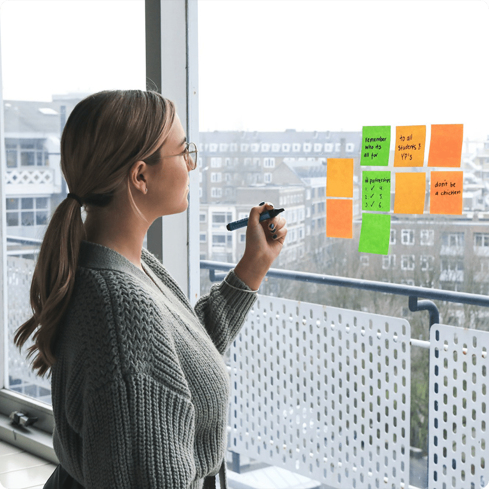 Chica apuntando en posits pegados en la ventana